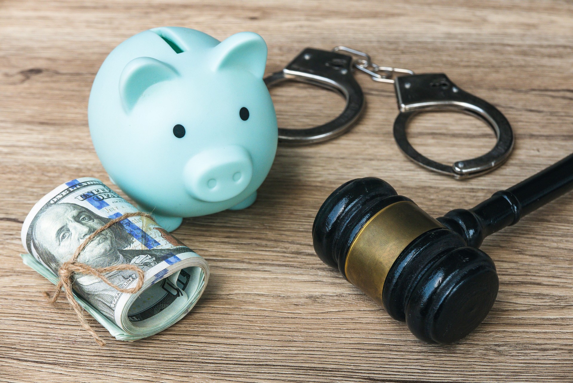 Financial Crime and Legal Consequences Concept with Piggy Bank, Handcuffs, Money Roll, and Gavel
